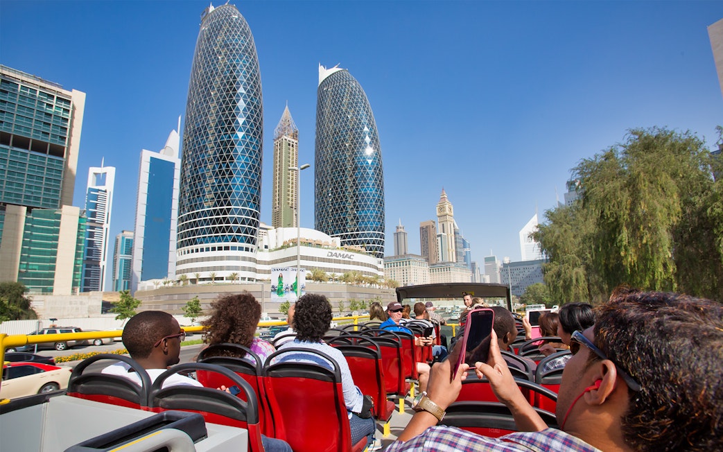 Open-top bus tour in Dubai with view of modern skyscrapers and cityscape.