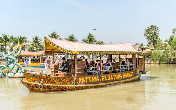Boat tour at Pattaya Floating Market with tourists and traditional decorations.