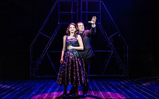 Actors performing on stage in a dramatic scene from the musical "Curtains.
