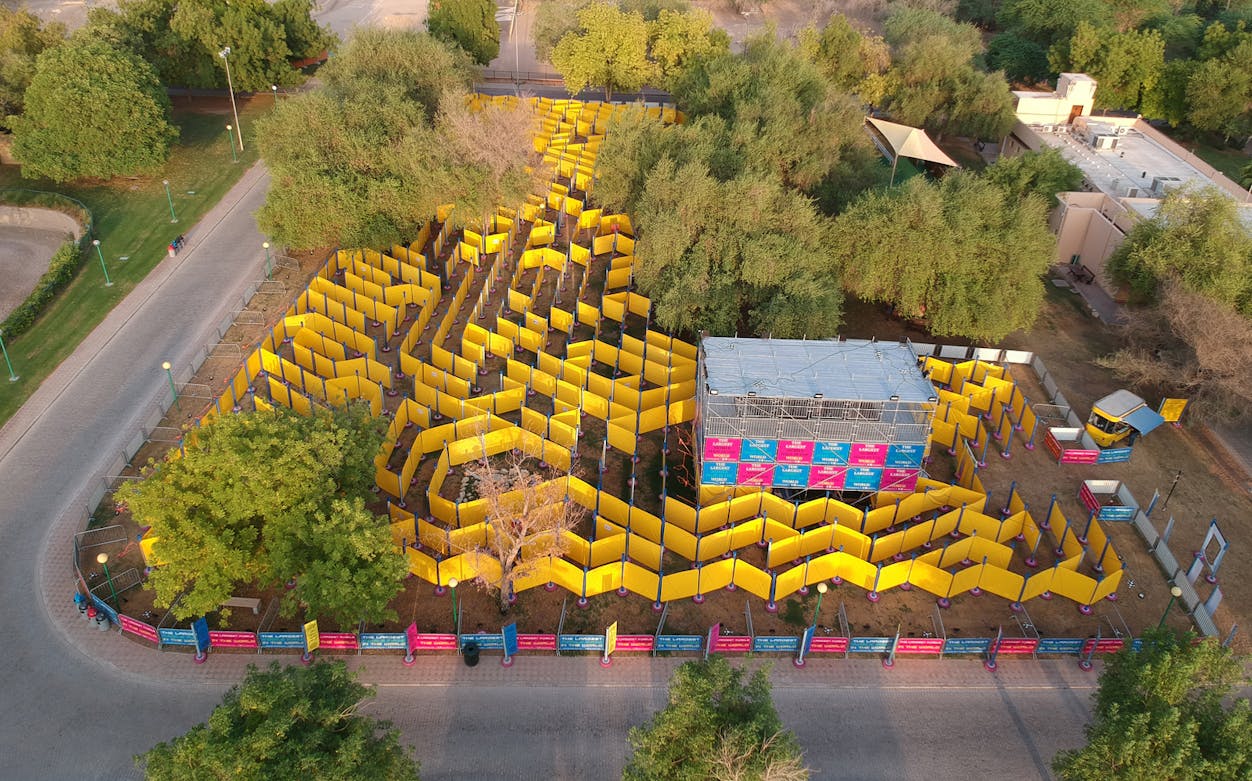 Aerial view of The Wonder Maze, the world’s largest mobile maze, with yellow walls in a park setting.