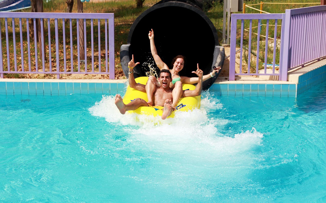 Two people enjoying a water slide at Dreamland Aquapark.