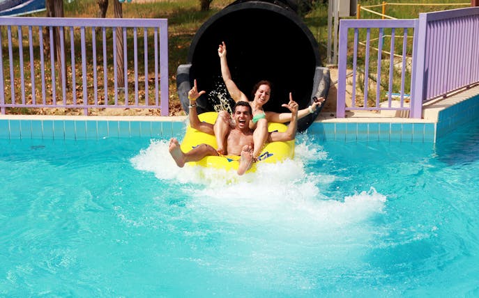 Two people enjoying a water slide at Dreamland Aquapark.