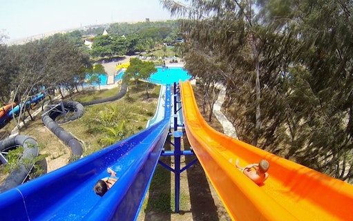 Two people sliding down colorful water slides at Dreamland Aquapark.