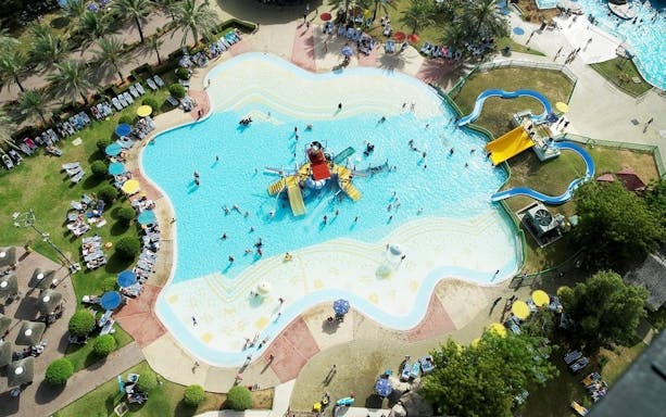 Aerial view of Dreamland Aquapark pool with slides and people swimming.
