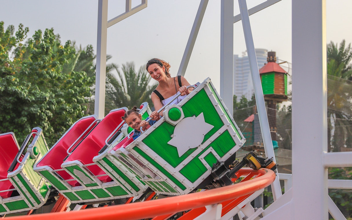 Roller coaster ride at Al Montazah Water Park with smiling riders.