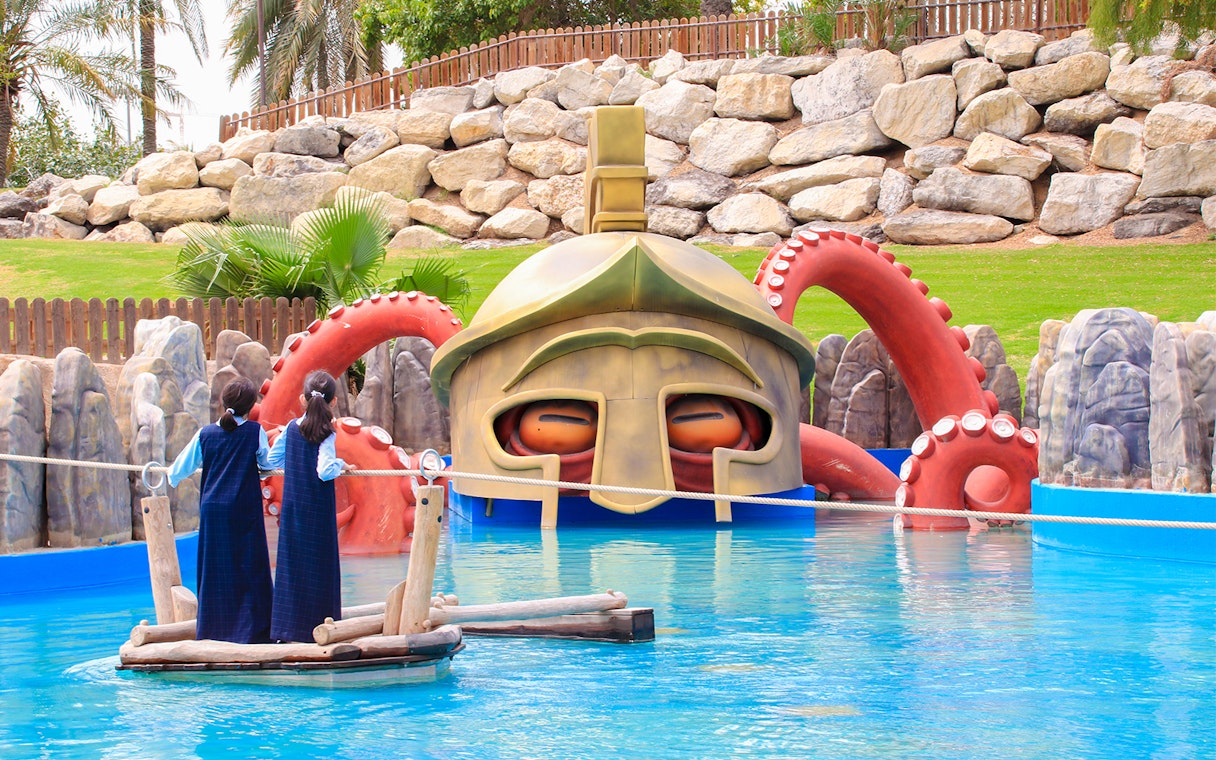 Children on a raft near a giant helmet and octopus tentacles at Al Montazah Water Park.