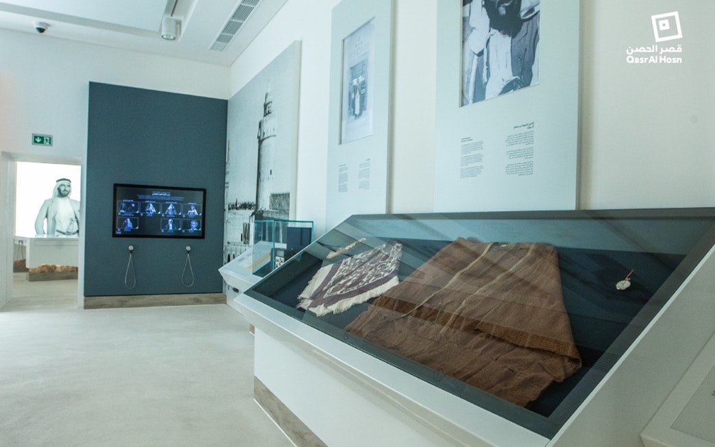 Exhibit of traditional garments and historical photos at Qasr Al Hosn museum, Abu Dhabi.