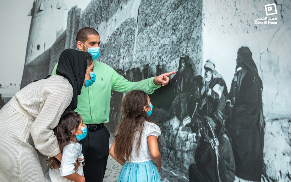 Family observing historical mural at Qasr Al Hosn, Abu Dhabi.