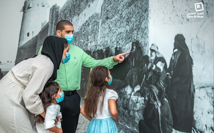 Family observing historical mural at Qasr Al Hosn, Abu Dhabi.