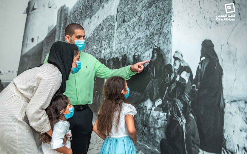Family observing historical mural at Qasr Al Hosn, Abu Dhabi.