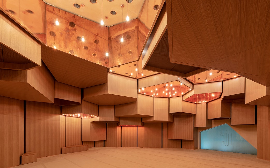 Interior of Qasr Al Hosn auditorium with geometric wooden panels and warm lighting.