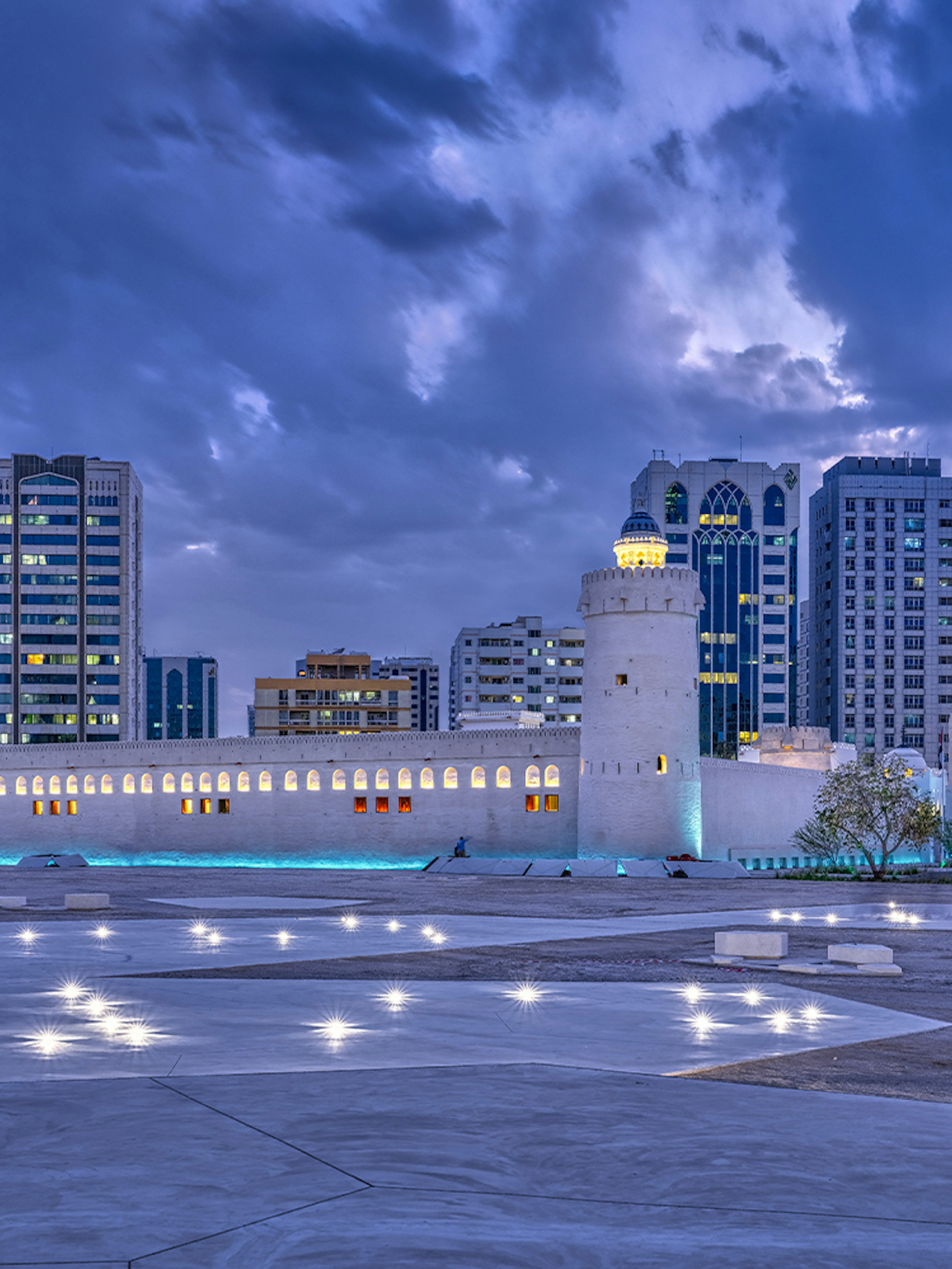 Qasr Al Hosn fortress in Abu Dhabi with modern skyline at dusk.
