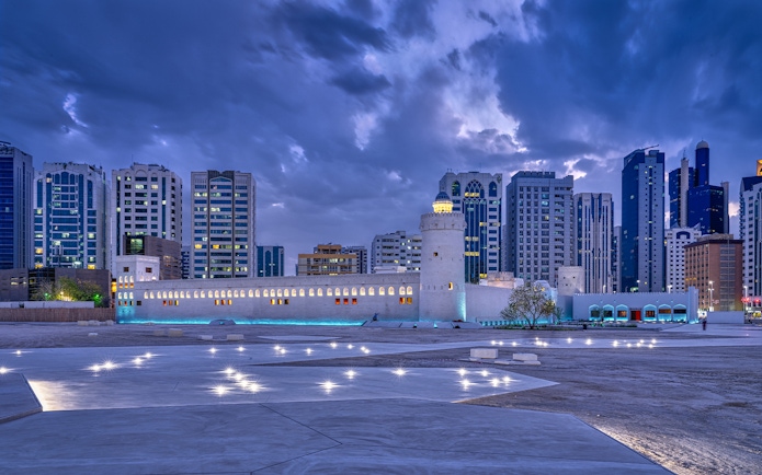 Qasr Al Hosn fortress in Abu Dhabi with modern skyline at dusk.