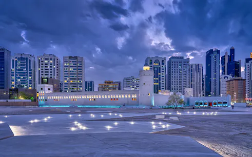 Qasr Al Hosn fortress in Abu Dhabi with modern skyline at dusk.