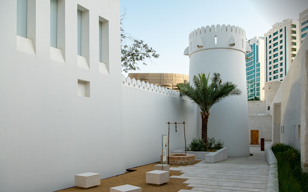 Qasr Al Hosn courtyard with historic tower and palm tree in Abu Dhabi.