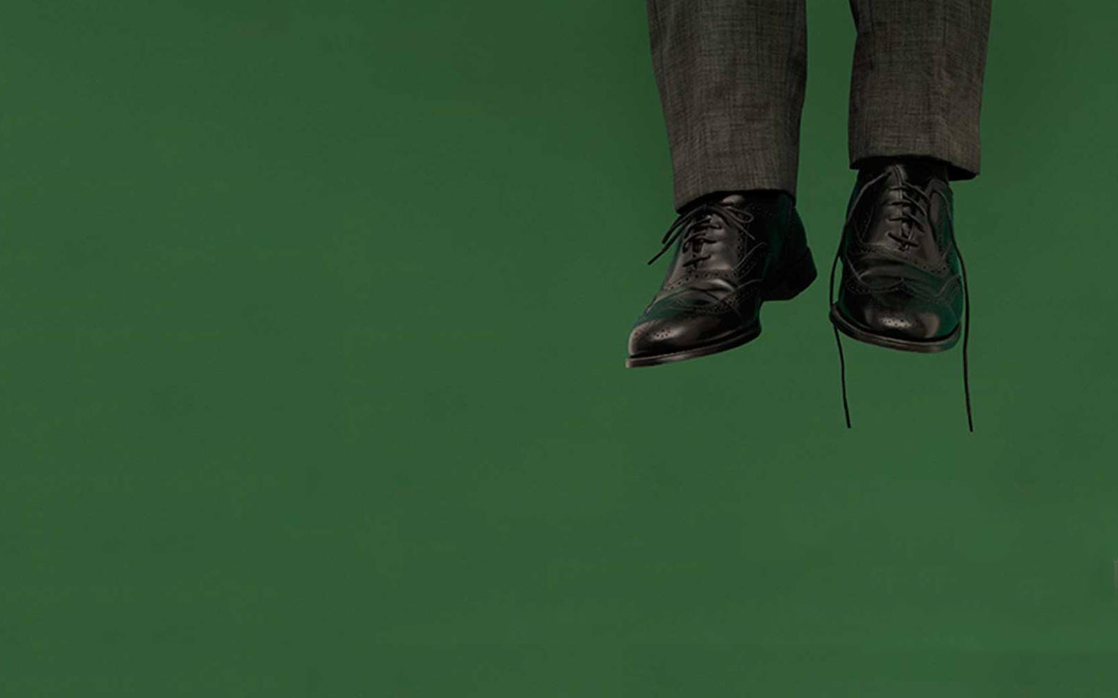 Formal shoes and trousers against a green background, related to "Hangmen" theme.