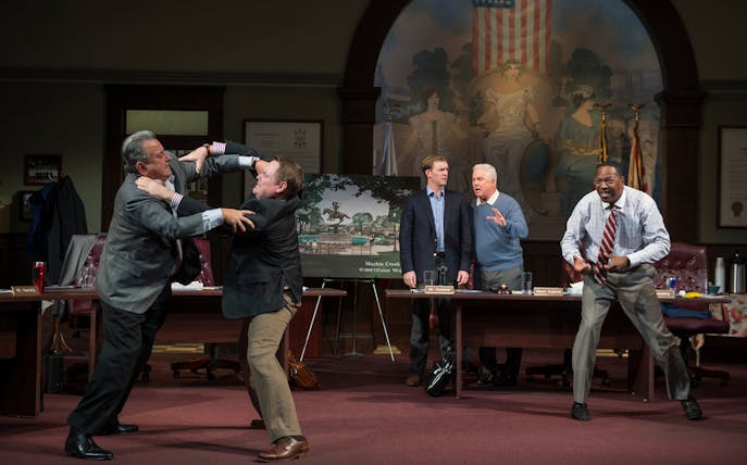 Council meeting scene with men in a heated argument, part of "The Minutes" play.