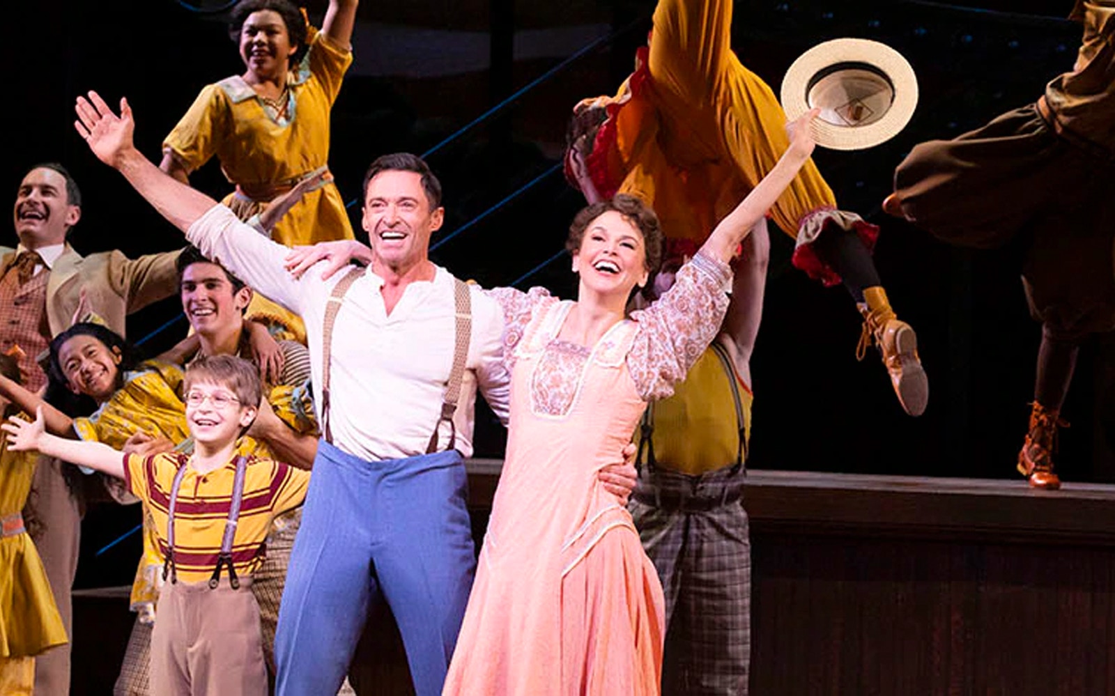 Cast performing a lively scene from "The Music Man" musical on stage.