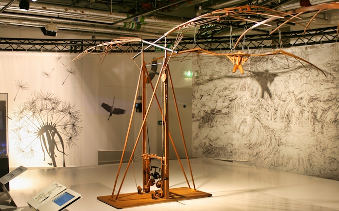 Leonardo Da Vinci Museum exhibit featuring a flying machine model with detailed sketches in the background.