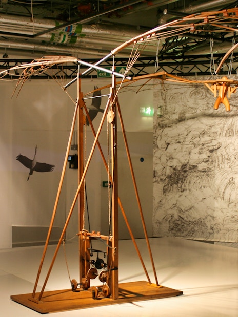 Leonardo Da Vinci Museum exhibit featuring a flying machine model with detailed sketches in the background.