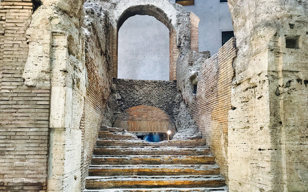 Ancient stone steps leading to an archway in Rome's underground near Navona Square.
