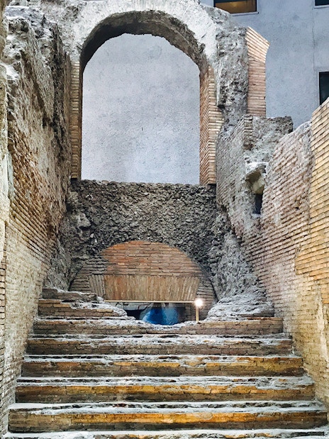 Ancient stone steps leading to an archway in Rome's underground near Navona Square.