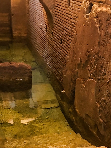 Ancient Roman brick walls and water channel in Rome's underground near Navona Square.