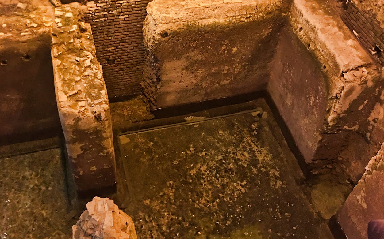 Ancient stone walls and water channel in Navona Underground, Rome.