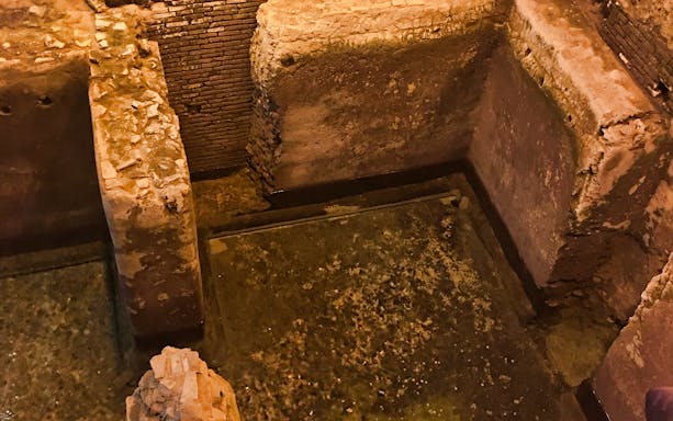 Ancient stone walls and water channel in Navona Underground, Rome.