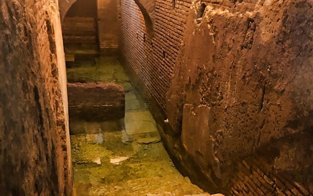 Trevi District Underground aqueduct with ancient brick walls and water channel.