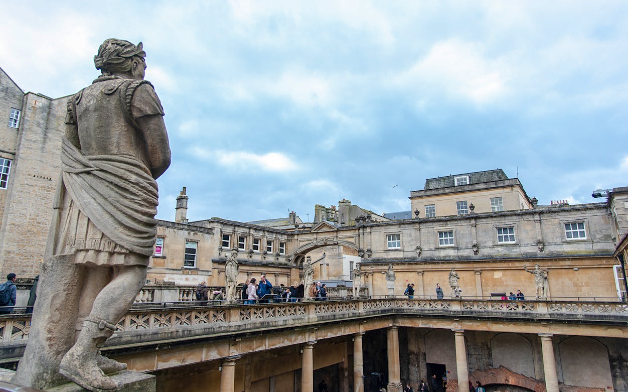 Statue overlooking the Baths of Diocletian courtyard with visitors exploring.