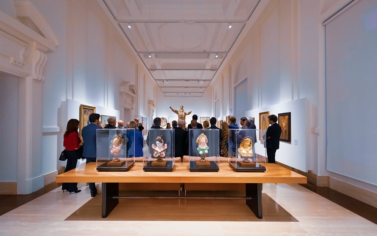 Visitors viewing art exhibits at Palazzo Merulana in Rome.