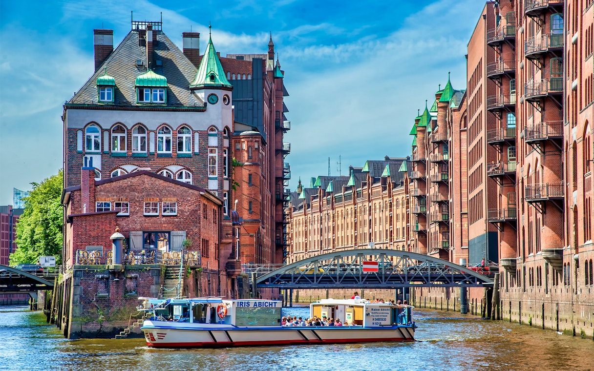 Boat cruising through Hamburg's Speicherstadt district with historic brick warehouses.