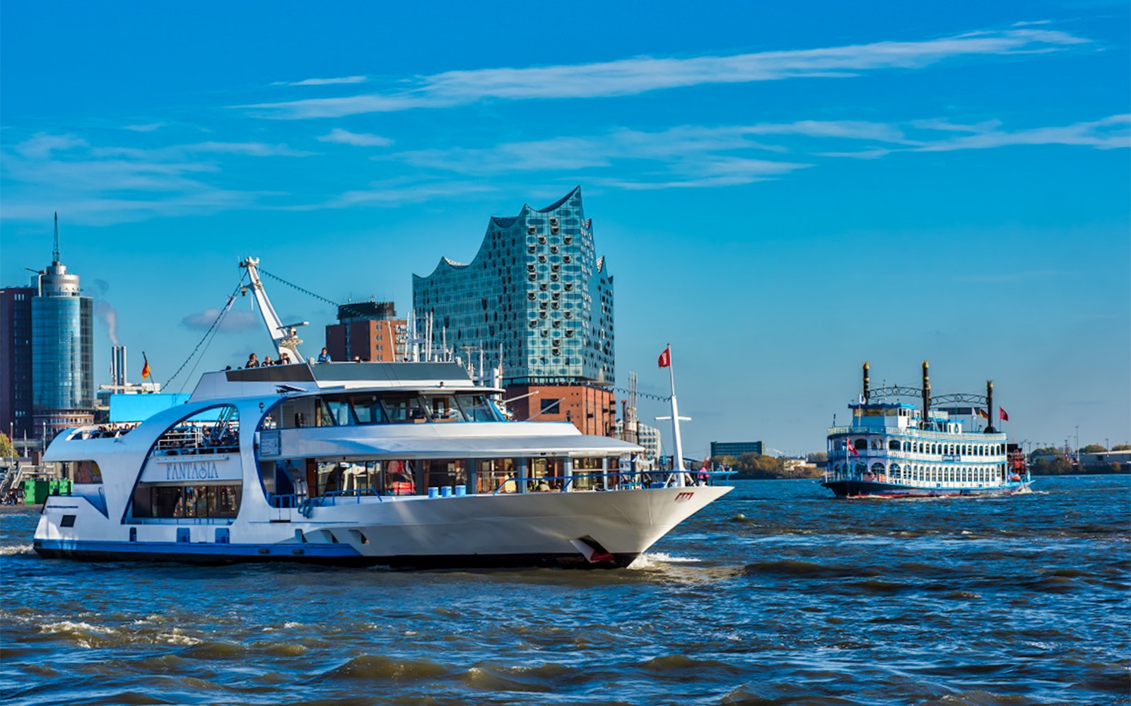 Hamburg River Cruise boat passing historic buildings along the Elbe River near Panoptikum.