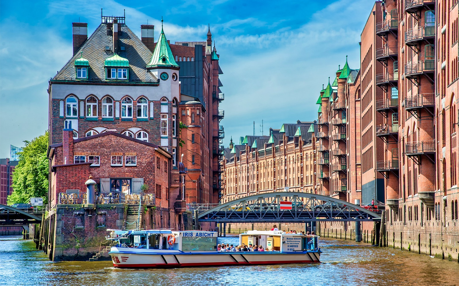 Hamburg River Cruise boat passing historic Speicherstadt warehouses on Elbe River.