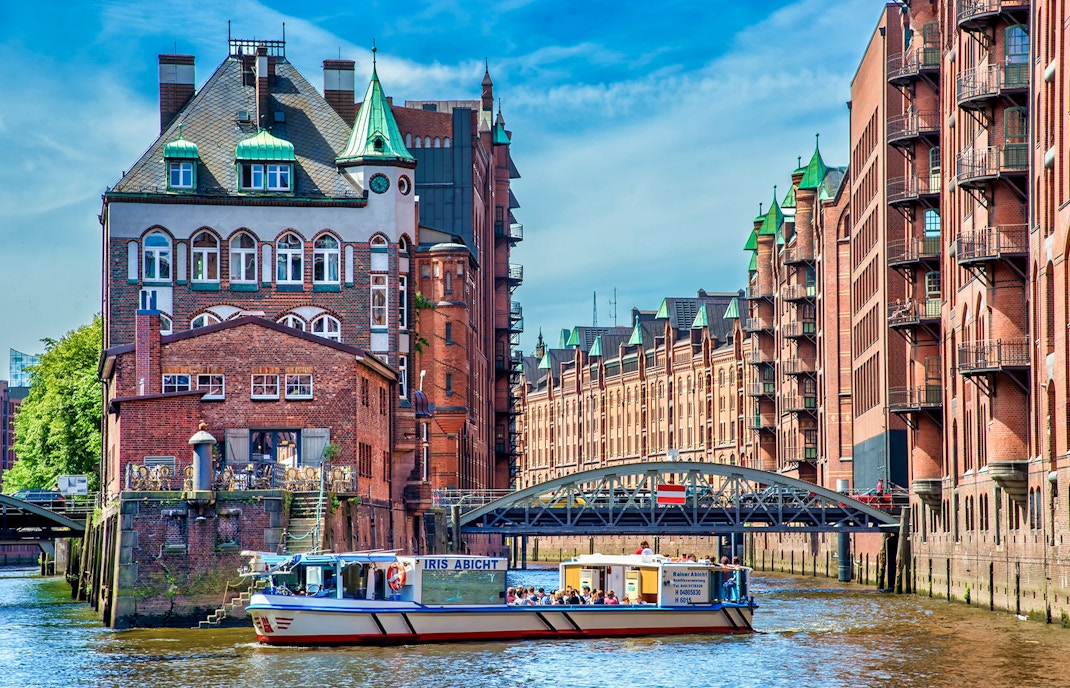 Hamburg River Cruise boat passing historic Speicherstadt warehouses on Elbe River.
