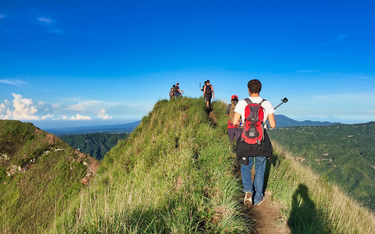 Hikers on Mount Batur trail during sunrise trek in Bali, Indonesia.