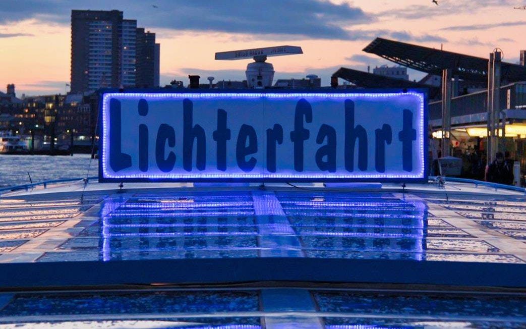 Hamburg Harbour evening cruise with illuminated "Lichterfahrt" sign on boat.