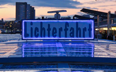 Hamburg Harbour evening cruise with illuminated "Lichterfahrt" sign on boat.