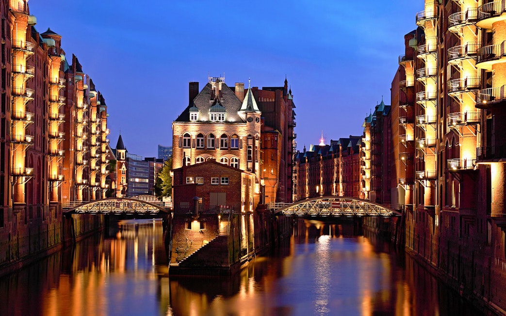 Illuminated Speicherstadt warehouses at night during Hamburg Harbour cruise.