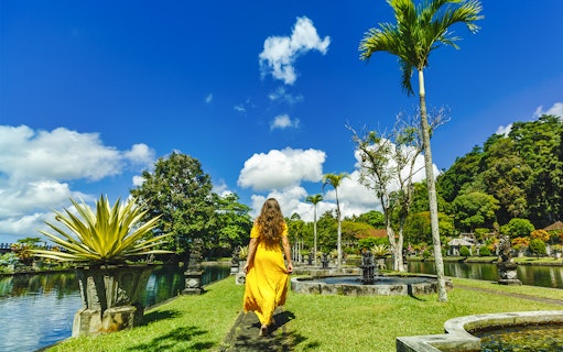 Woman walking through Tirta Gangga Water Palace gardens in Bali.