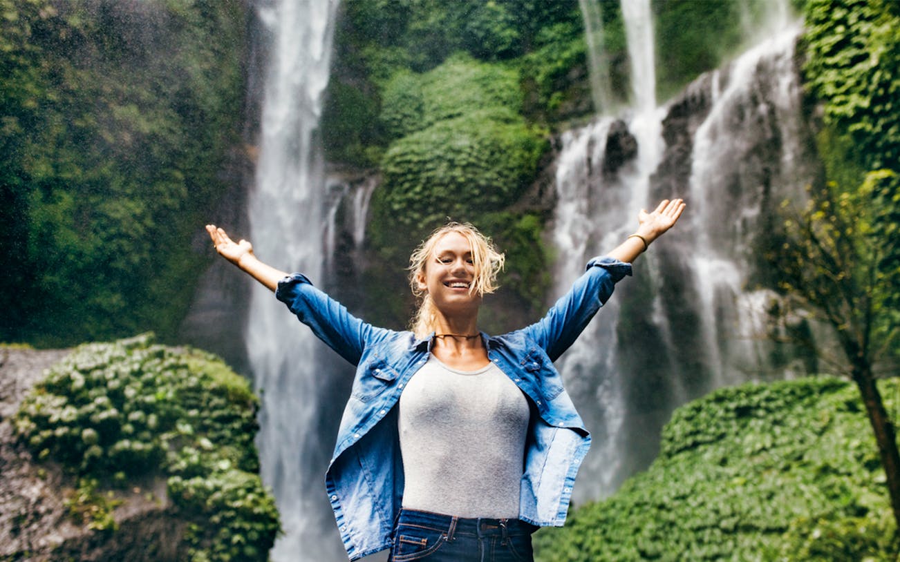 Person enjoying lush waterfall on Best of Bali Waterfalls Tour.