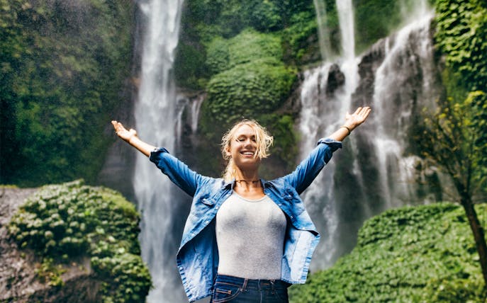 Person enjoying lush waterfall on Best of Bali Waterfalls Tour.
