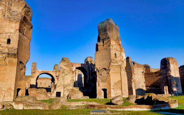 Ruins of the Baths of Caracalla in Rome under a clear blue sky.