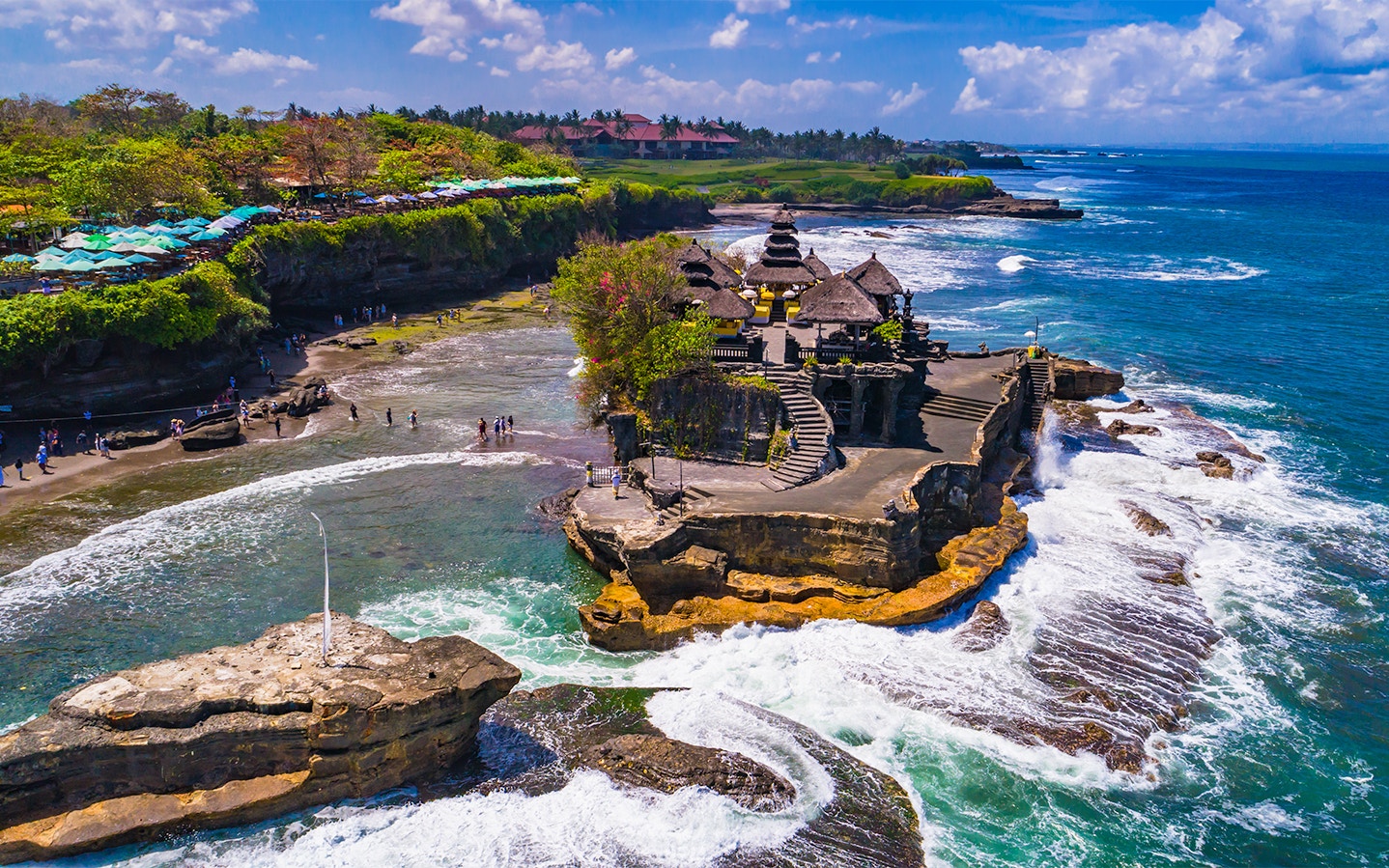 Tanah Lot Temple on a rocky outcrop surrounded by ocean waves in Bali, Indonesia.