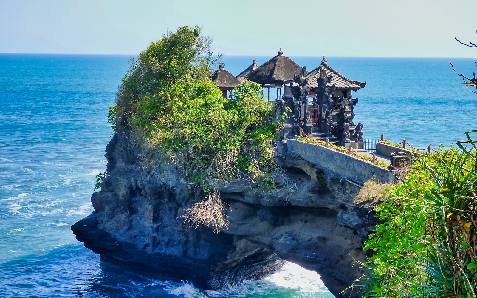 Bali's Tanah Lot Temple on a rocky cliff by the sea.