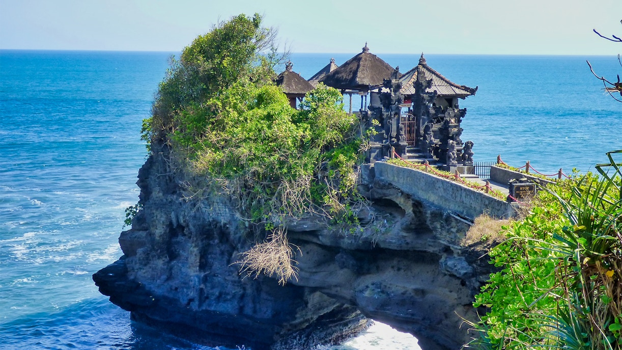 Bali's Tanah Lot Temple on a rocky cliff by the sea.