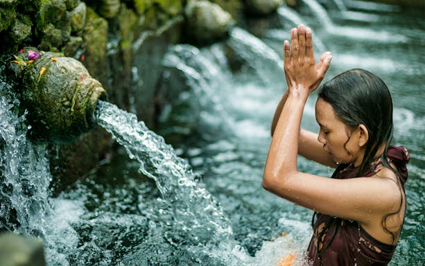 Balinese woman performing ritual at Tirta Empul Temple, Bali.