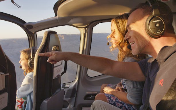 Helicopter passengers enjoying Grand Canyon view during tour with Las Vegas Strip flyover.