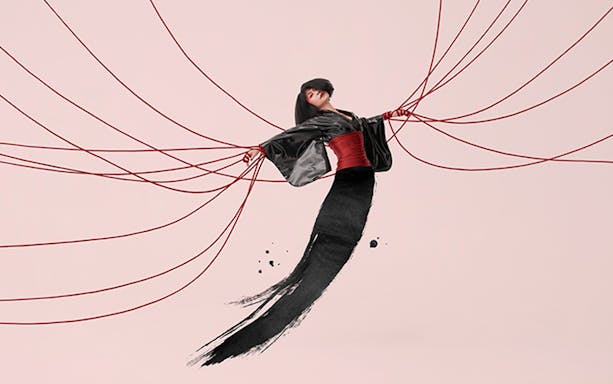 Performer in traditional attire with red cords, promoting Madama Butterfly on Sydney Harbour.